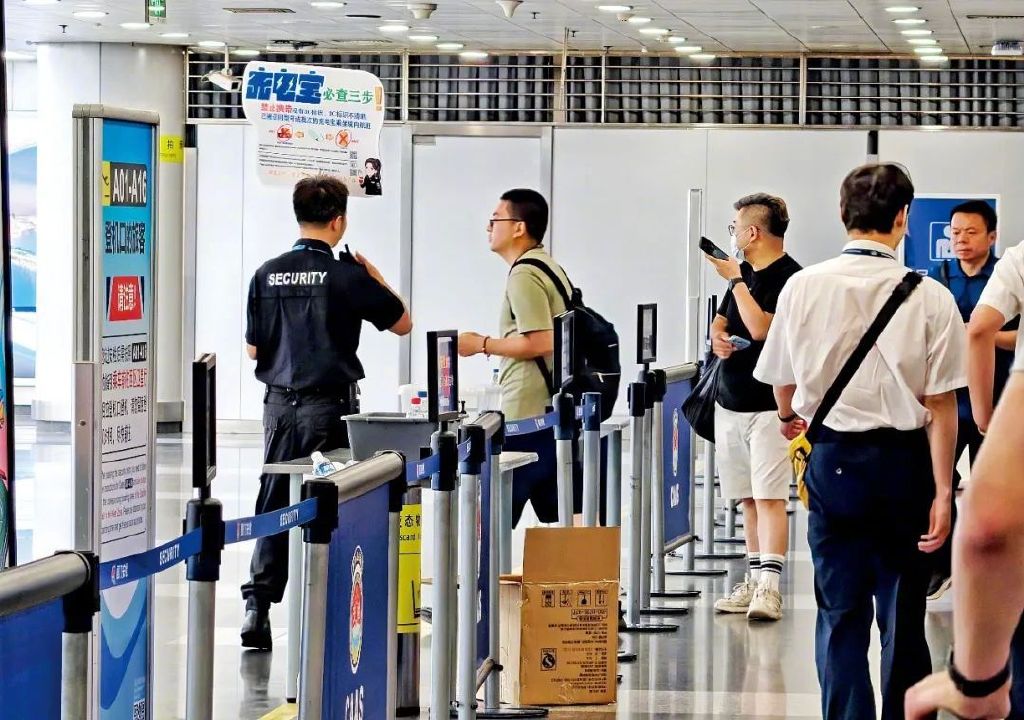 6月28日,北京首都国际机场安检区域,工作人员提示旅客检查充电宝。图/视觉中国