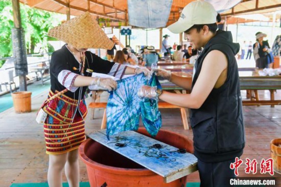 6月9日,印尼博主陈浩杰(右一)在海南槟榔谷黎苗文化旅游区体验苗族扎染。(海南省国际文化交流中心 供图)