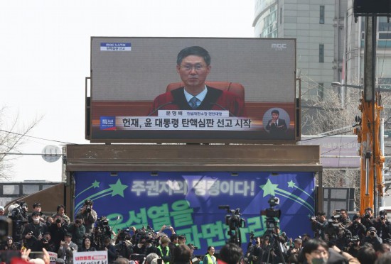 4月4日,民众在韩国首都首尔的韩国宪法法院附近观看尹锡悦弹劾案宣判过程的电视直播。新华社记者姚琪琳摄