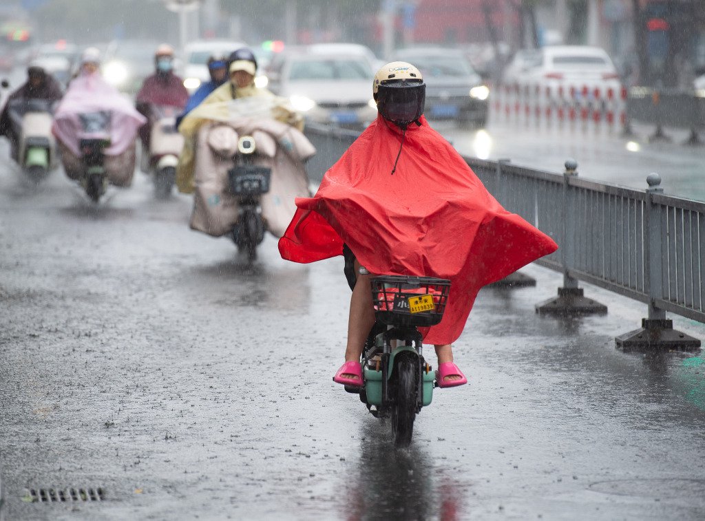 2025年6月20日，江苏省淮安市，市民冒雨在市区健康东路上出行。视觉中国 图