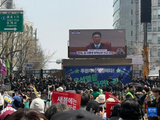 4月4日,人们在韩国首都首尔的韩国宪法法院附近观看尹锡悦弹劾案宣判过程的电视直播(手机照片)。新华社记者 姚琪琳 摄