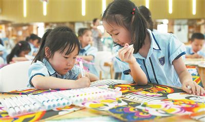 图为小朋友在制作纸鸢。本报记者 何亮摄