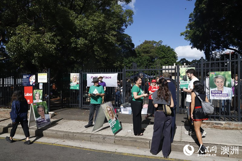 志愿者在投票站外向选民分发宣传单(摄影 刘美鹭)