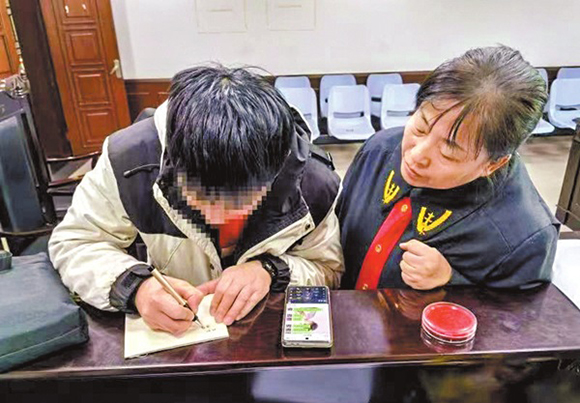 图为江苏省徐州市鼓楼区人民法院法官张向阳(右)用书写和微信打字的形式,与听障当事人”交流“案情。王蕴竹 摄