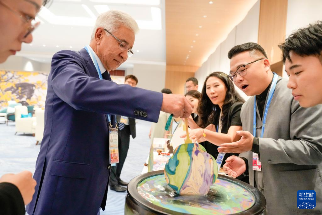 8月31日晚,贵宾们在欢迎宴会前体验制作漆扇。
