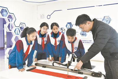 在山东日照金海岸小学,老师指导学生练习机械臂毛笔书写编程。新华社记者 郭绪雷摄